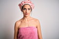 Young brunette woman with blue eyes wearing bath towel and shower cap with serious expression on face Royalty Free Stock Photo