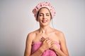 Young brunette woman with blue eyes wearing bath towel and shower cap smiling with hands on chest with closed eyes and grateful Royalty Free Stock Photo