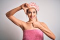 Young brunette woman with blue eyes wearing bath towel and shower cap smiling making frame with hands and fingers with happy face Royalty Free Stock Photo