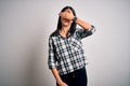 Young brunette woman with blue eyes wearing casual shirt and glasses over white background covering eyes with hand, looking