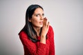 Young brunette woman with blue eyes wearing casual sweater over isolated white background hand on mouth telling secret rumor, Royalty Free Stock Photo