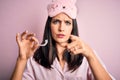 Young brunette woman with blue eyes wearing pajama holding dentist clear aligner pointing with finger to the camera and to you, Royalty Free Stock Photo