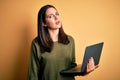 Young brunette woman with blue eyes working using computer laptop over yellow background looking sleepy and tired, exhausted for Royalty Free Stock Photo