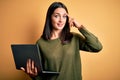 Young brunette woman with blue eyes working using computer laptop over yellow background Smiling pointing to head with one finger, Royalty Free Stock Photo