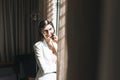 Young brunette woman business lady in white suit with mobile in the hotel room