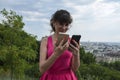 Young brunette woman choose between two cell phones. Girl looks at mobile, selecting color - black or white Royalty Free Stock Photo