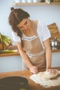 Young brunette woman cooking pizza or handmade pasta in the kitchen. Housewife preparing dough on wooden table. Dieting Royalty Free Stock Photo