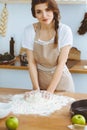 Young brunette woman cooking pizza or handmade pasta in the kitchen. Housewife preparing dough on wooden table. Dieting Royalty Free Stock Photo