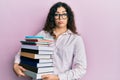 Young brunette woman with curly hair holding a pile of books depressed and worry for distress, crying angry and afraid Royalty Free Stock Photo