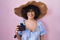 Young brunette woman with curly hair using reflex camera looking positive and happy standing and smiling with a confident smile Royalty Free Stock Photo