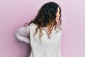 Young brunette woman with curly hair wearing casual clothes suffering of backache, touching back with hand, muscular pain Royalty Free Stock Photo