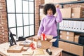 Young brunette woman with curly hair working at small business ecommerce preparing order annoyed and frustrated shouting with