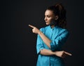 Young brunette woman doctor nurse in blue medical gown points with fingers in different directions diagonal Royalty Free Stock Photo