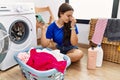 Young brunette woman doing laundry using smartphone tired rubbing nose and eyes feeling fatigue and headache Royalty Free Stock Photo