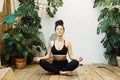 Young woman with dreadlocks practices yoga at home among flowers. Urban jungle and gymnastics, yoga, pilates. Royalty Free Stock Photo