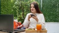 Young brunette woman drinking tea and and working on laptop at summer terrace Royalty Free Stock Photo