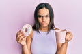 Young brunette woman eating doughnut and drinking coffee depressed and worry for distress, crying angry and afraid Royalty Free Stock Photo