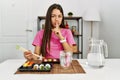 Young brunette woman eating sushi using chopsticks asking to be quiet with finger on lips Royalty Free Stock Photo