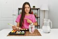 Young brunette woman eating sushi using chopsticks pointing aside worried and nervous with forefinger, concerned and surprised Royalty Free Stock Photo