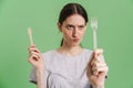 Young brunette woman frown while showing disposable forks