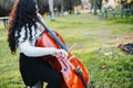 close up of a brunette woman with glasses playing cello at sunset in the park, on a green grass. Royalty Free Stock Photo