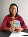 young brunette woman grabbing and showing New Zealand money