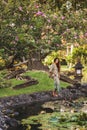 Young brunette woman in green dress walking in japanese garden stone waterfront
