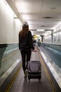 Young brunette woman with her luggage in an airport concourse.