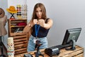 Young brunette woman holding banner with open text at retail shop punching fist to fight, aggressive and angry attack, threat and