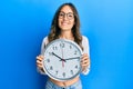 Young brunette woman holding big clock smiling with a happy and cool smile on face Royalty Free Stock Photo