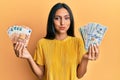 Young brunette woman holding bunch of dollars and euros puffing cheeks with funny face Royalty Free Stock Photo