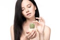 Young brunette woman holding cactus in pot and touching thorns