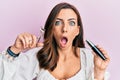 Young brunette woman holding eyelash curler afraid and shocked with surprise and amazed expression, fear and excited face Royalty Free Stock Photo