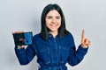 Young brunette woman holding hdd disk smiling with an idea or question pointing finger with happy face, number one Royalty Free Stock Photo