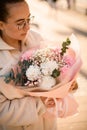 Young brunette woman holding huge beautiful bouquet of fresh pink and white carnations and green eucalyptus branches in Royalty Free Stock Photo