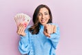 Young brunette woman holding 20 israel shekels banknotes pointing to you and the camera with fingers, smiling positive and Royalty Free Stock Photo