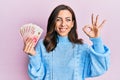 Young brunette woman holding 20 israel shekels banknotes smiling positive doing ok sign with hand and fingers Royalty Free Stock Photo