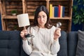 Young brunette woman holding led lightbulb and lamp depressed and worry for distress, crying angry and afraid