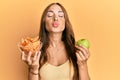 Young brunette woman holding nachos and healthy green apple looking at the camera blowing a kiss being lovely and sexy Royalty Free Stock Photo