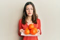 Young brunette woman holding plate with fresh oranges relaxed with serious expression on face Royalty Free Stock Photo