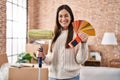 Young brunette woman holding roller painter and paint samples smiling with a happy and cool smile on face Royalty Free Stock Photo