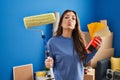 Young brunette woman holding roller painter painting new house looking at the camera blowing a kiss being lovely and sexy Royalty Free Stock Photo