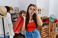 Young brunette woman holding shopping bags at retail shop doing ok gesture shocked with surprised face, eye looking through Royalty Free Stock Photo