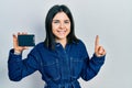 Young brunette woman holding ssd memory smiling with an idea or question pointing finger with happy face, number one Royalty Free Stock Photo