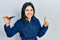 Young brunette woman holding ssd memory smiling with an idea or question pointing finger with happy face, number one Royalty Free Stock Photo