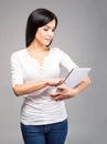 Young brunette woman holding a tablet computer on grey Royalty Free Stock Photo