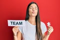 Young brunette woman holding team paper and piece of puzzle as teamwork looking at the camera blowing a kiss being lovely and sexy