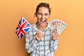 Young brunette woman holding uk flag and pounds banknotes smiling and laughing hard out loud because funny crazy joke