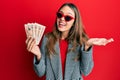 Young brunette woman holding united kingdom 10 pounds banknotes celebrating achievement with happy smile and winner expression