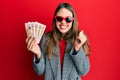 Young brunette woman holding united kingdom 10 pounds banknotes screaming proud, celebrating victory and success very excited with